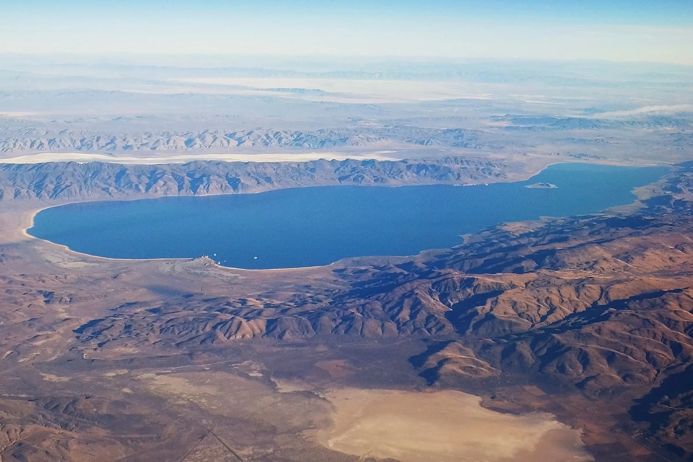 Aerial view of Pyramid Lake, a long blue lake ringed by brown desert mountains north of Reno